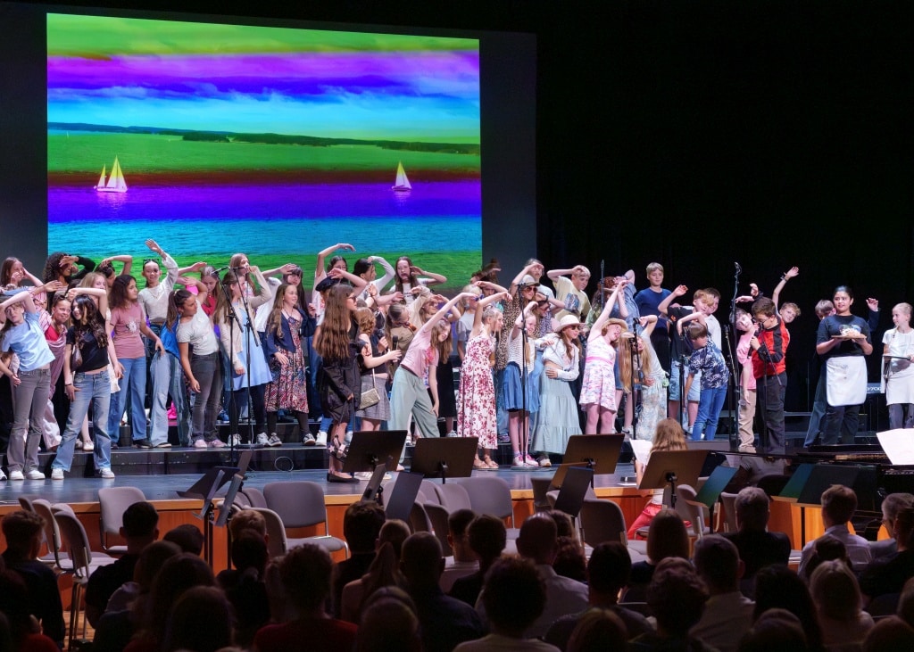 Kinderchor in Theateraufführung Kinderchoraufführung mit buntem Hintergrundbild und Publikum im Theater