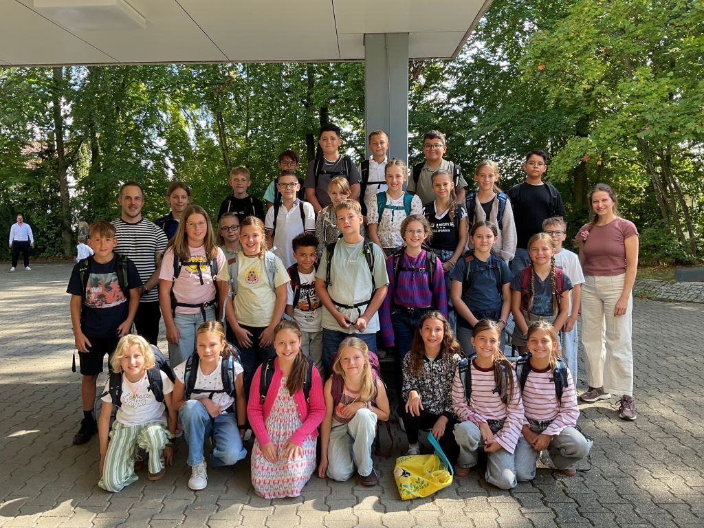 Gruppe von Schulkindern mit Lehrern vor grünem Hintergrund